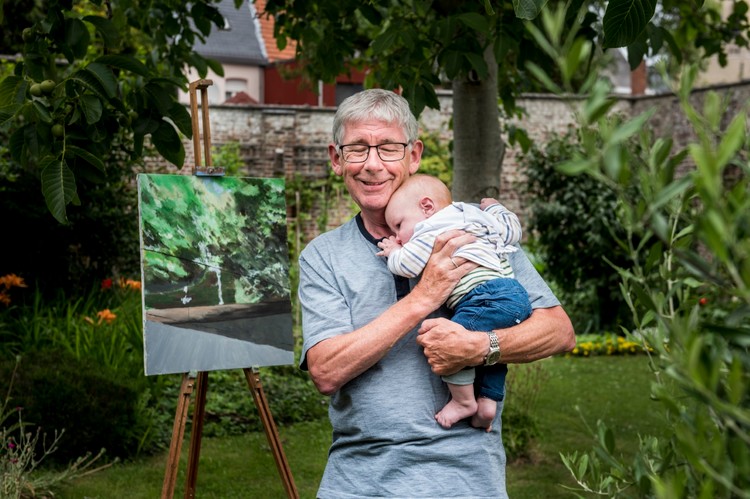 Jan staat in zijn tuin en knuffelt kleinkind Monk